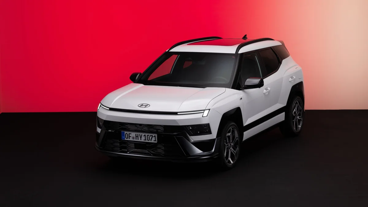 Witte nieuwe Hyundai Bayon van schuin voren voor een rode achtergrond