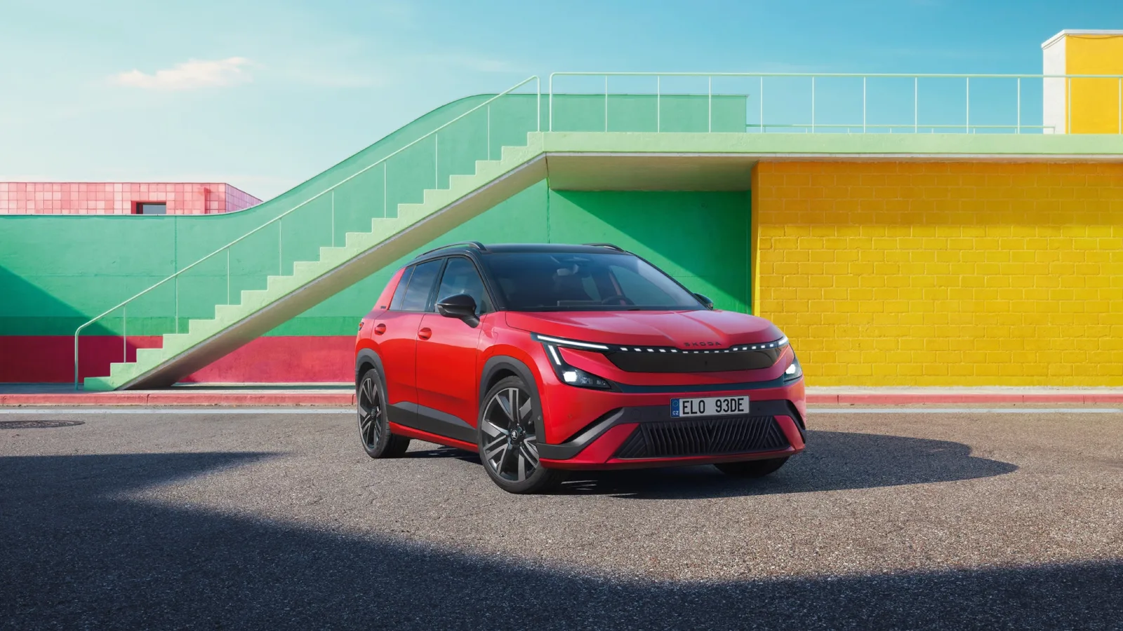 Rode Škoda Epiq Sportline met zwart dak van schuin voren voor kleurrijke gebouwen