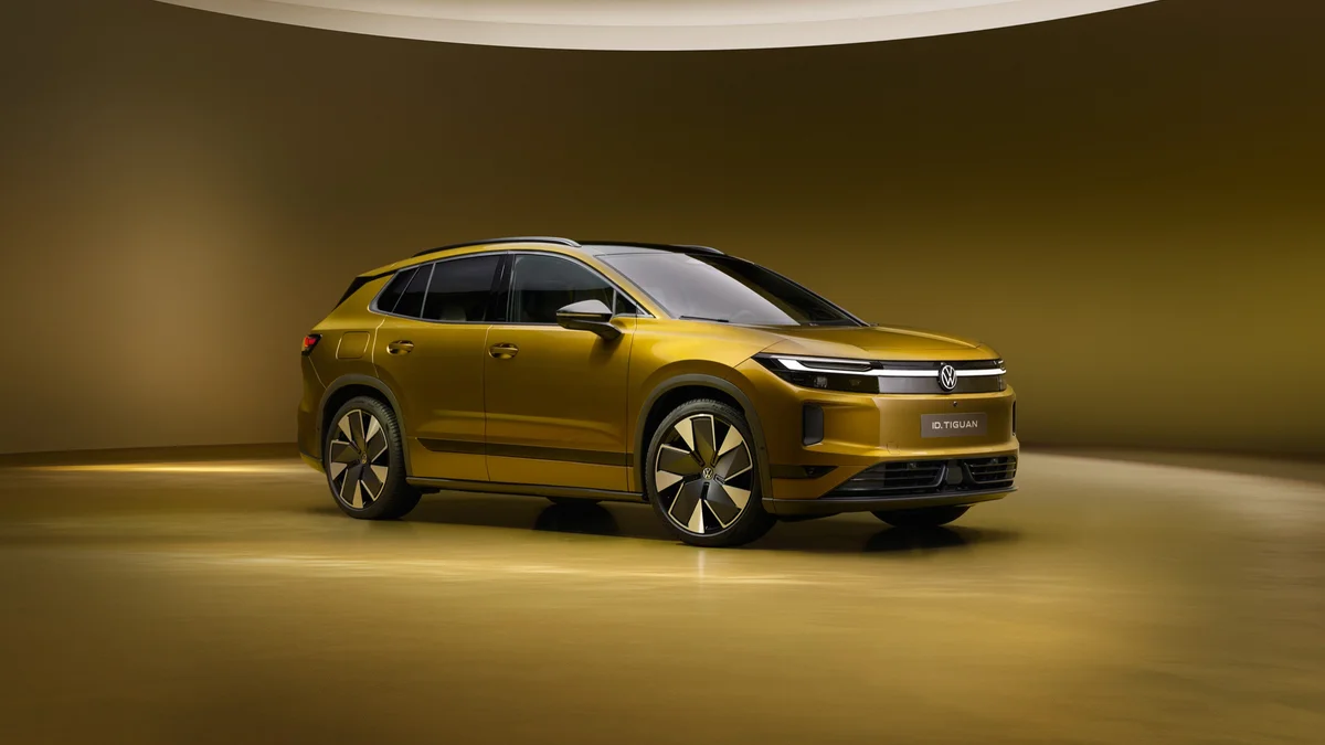 Goudkleurige Volkswagen ID. Tiguan Style van schuin voren in een studio met warm licht
