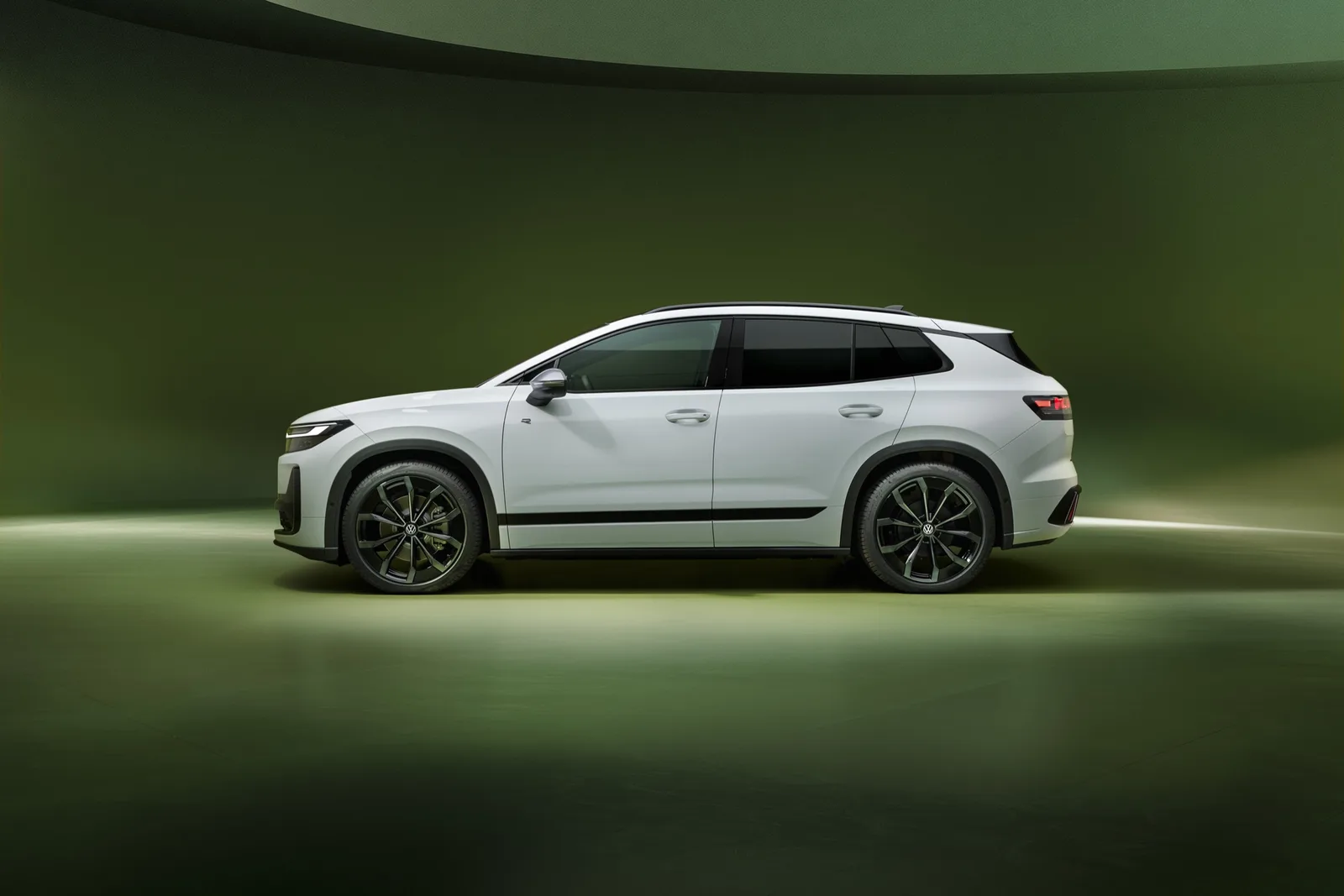 Witte Volkswagen ID. Tiguan R-Line van opzij in een groene studio