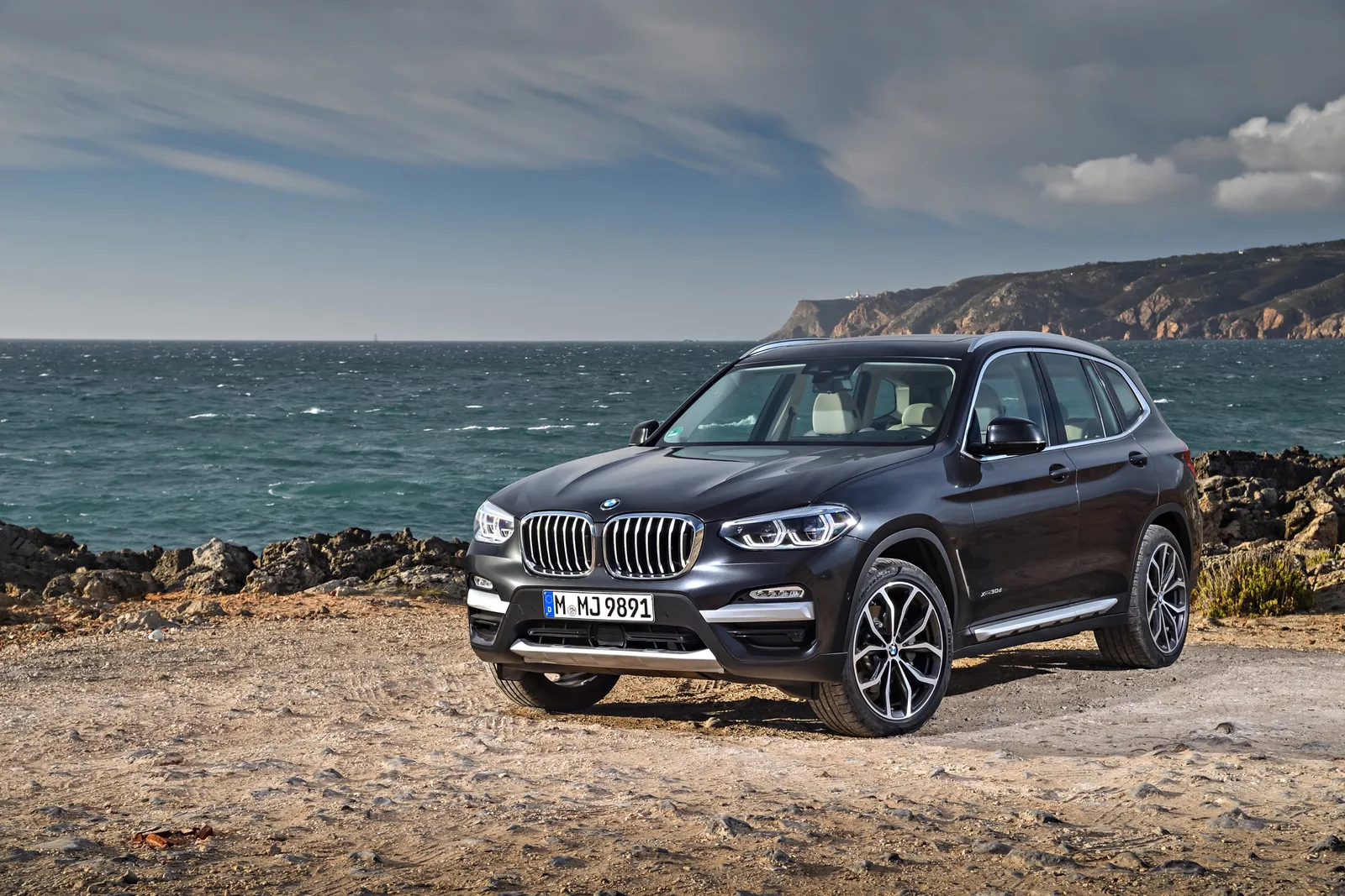Donkergrijze BMW X3 van de G01-generatie aan de kust