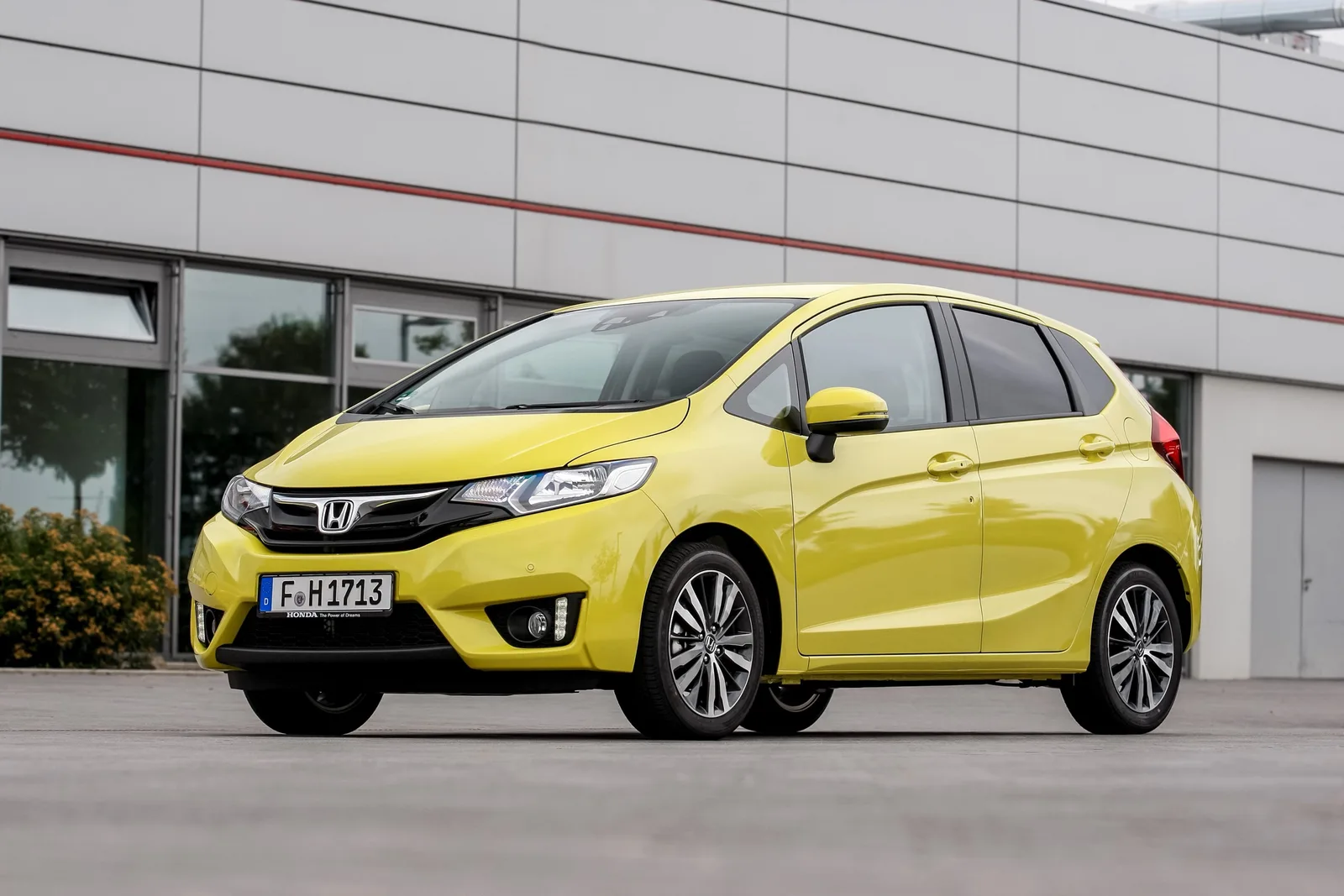 Gele Honda Jazz van de derde generatie van schuin voren voor een gebouw