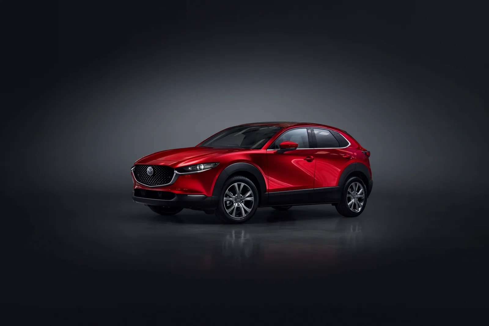 Rode Mazda CX-30 van schuin voren in een donkere studio