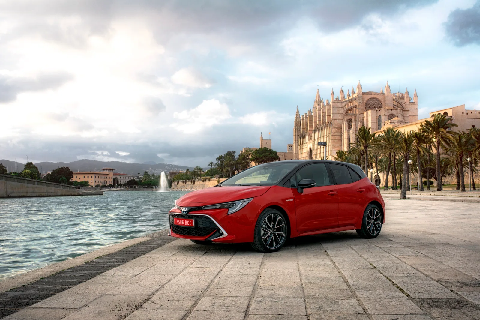 Rode Toyota Corolla hatchback van de E210-generatie aan het water