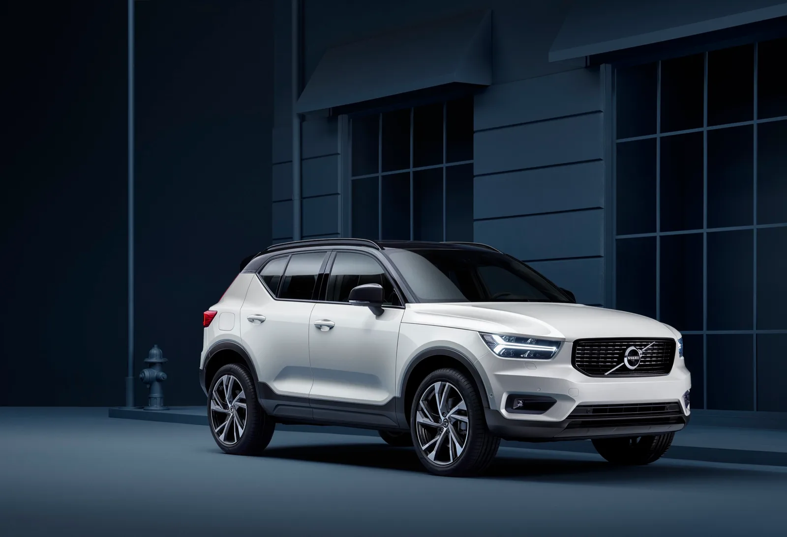 Witte Volvo XC40 met zwart dak van schuin voren voor een donker gebouw