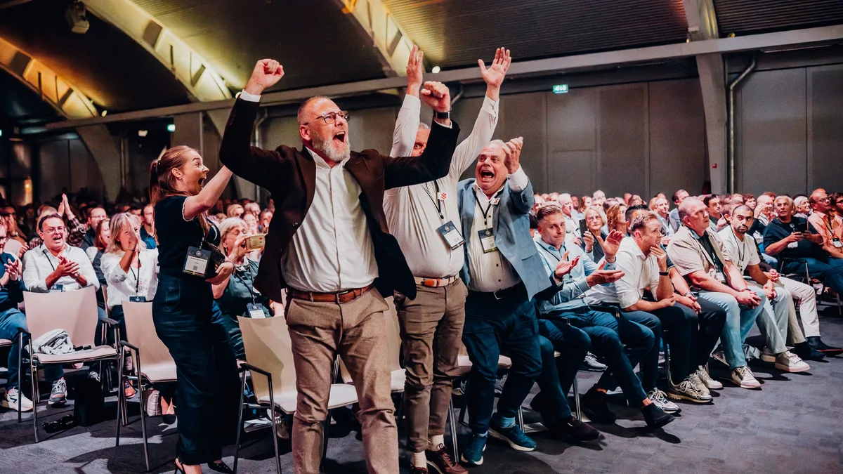 Juichende mensen met de armen in de lucht in een volle zaal bij de prijsuitreiking tijdens BOVAG Supercharge 2026